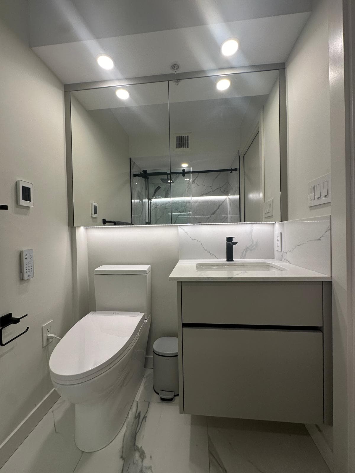 Modern bathroom with floating vanity, marble tile, and glass shower enclosure